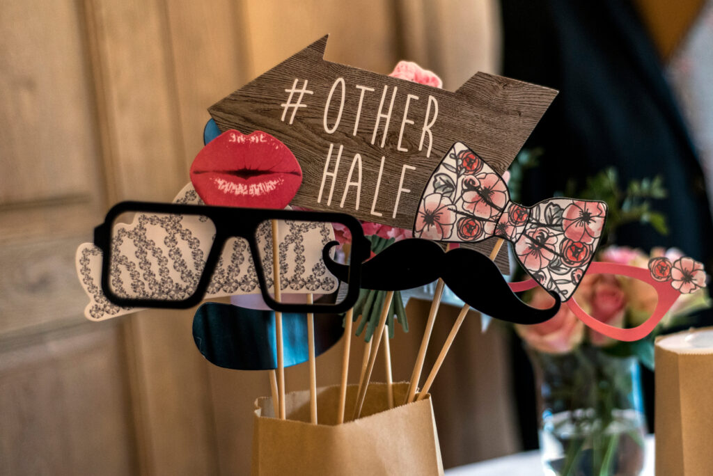 Photo booth props for a party, including a sign with '#OTHER HALF', lips, glasses, and a mustache.